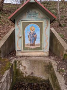 Eingefasste Heiligen-Quelle, die dazu einlädt "sich zu laben".Darunter ein Schild "Kein Trinwasser".